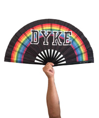 A black folding hand fan with a rainbow graphic and the word 'DYKE' in white block letters
