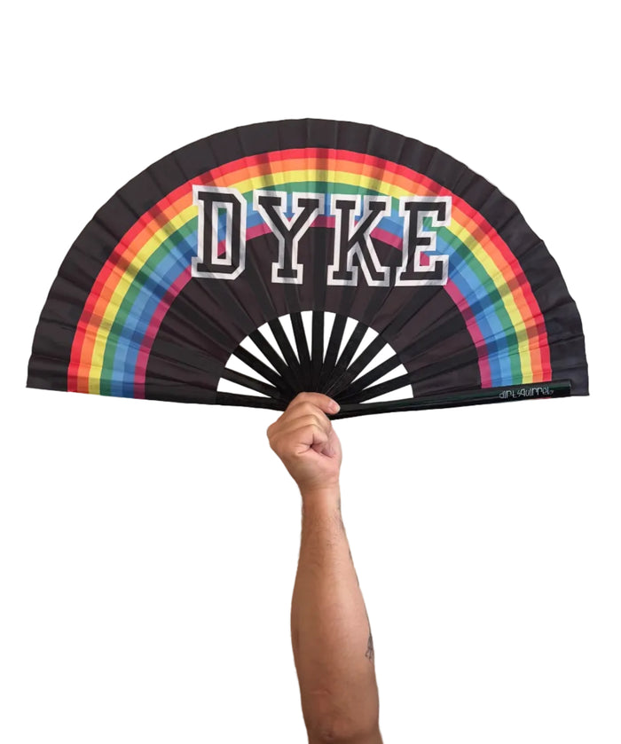 A black folding hand fan with a rainbow graphic and the word 'DYKE' in white block letters